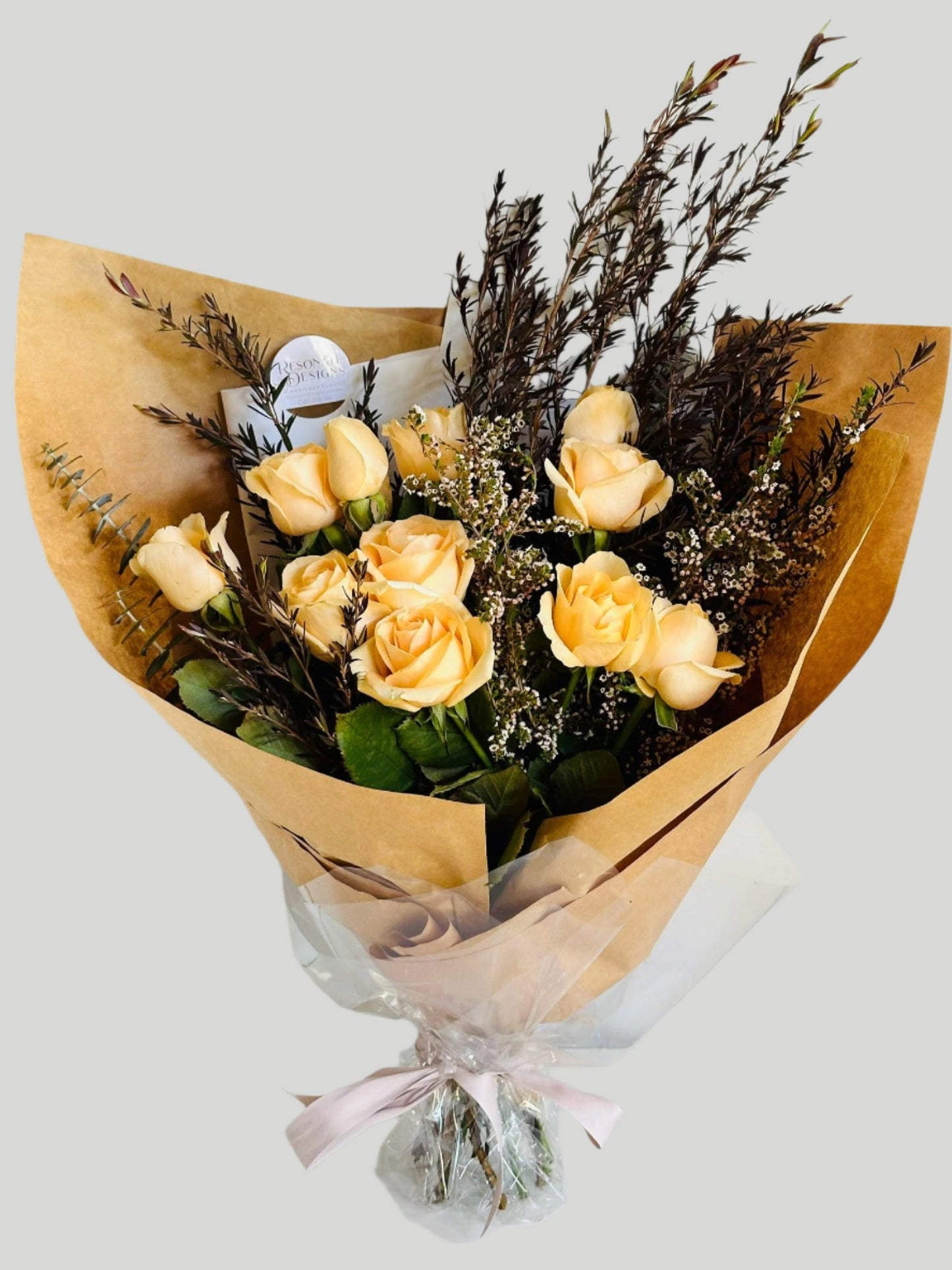 peach roses gift wrapped in brown craft paper finished with beautiful foliage for delivery on the Sunshine Coast