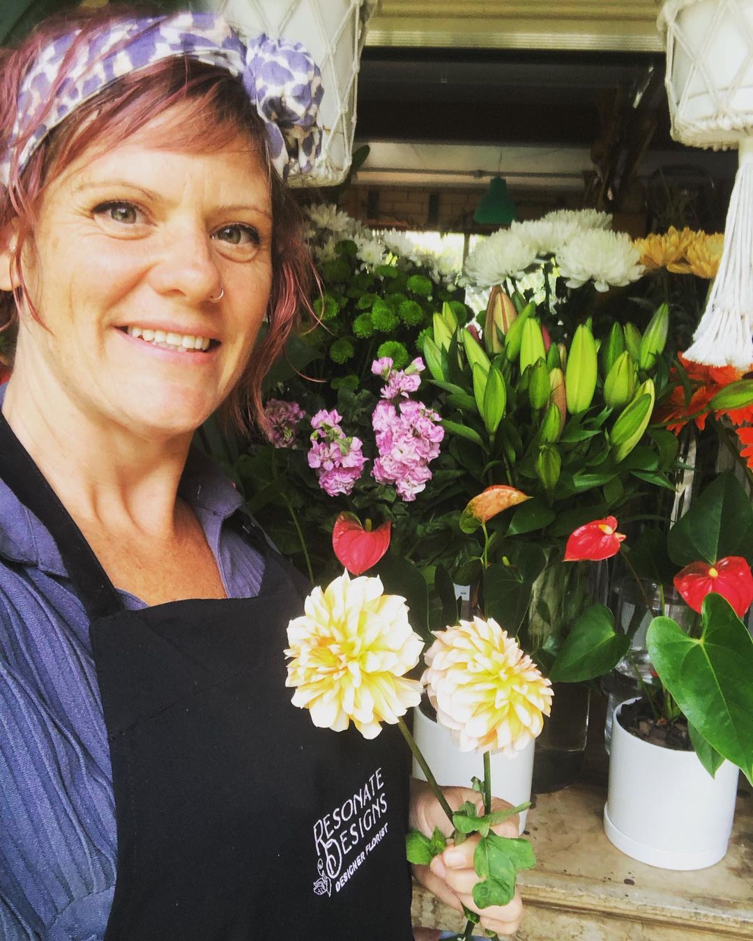 Mandi the florist at Resonate Designs florist on the Sunshine Coast standing in front of an array of flowers.